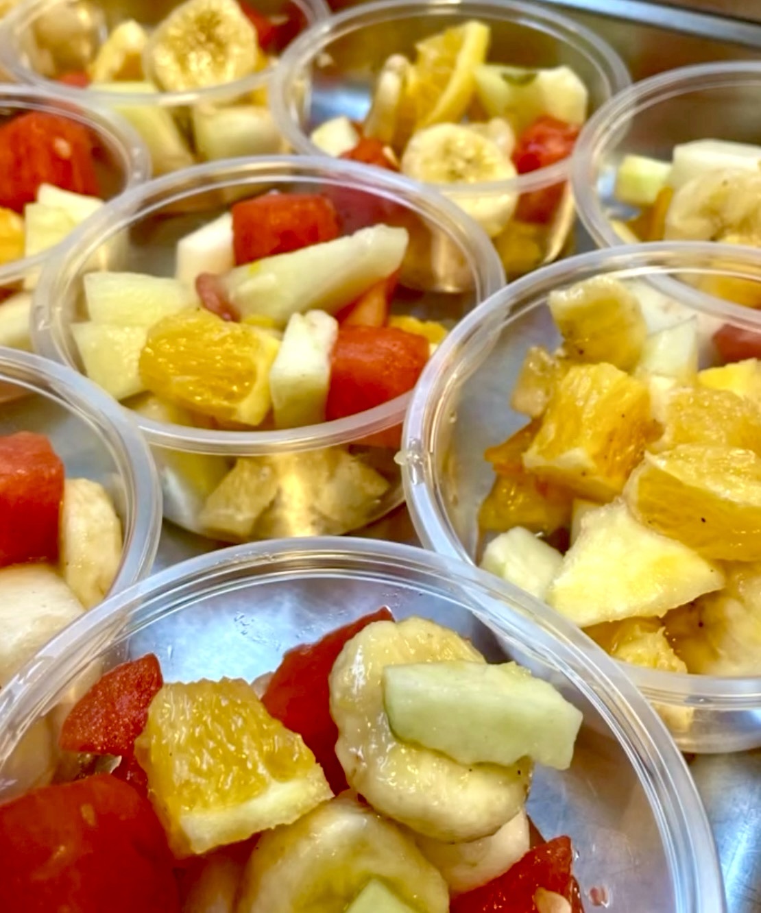 Närbild på fruktsallad i genomskinliga platsbehållare.